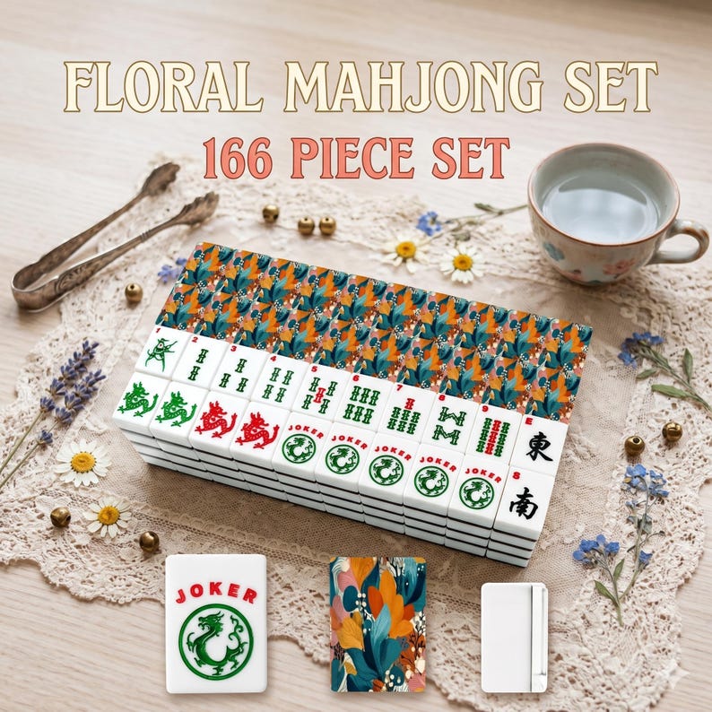 May include: A floral Mahjong set with 166 pieces. The tiles are white with green, red, and black symbols. The set includes a decorative box with a colorful floral pattern. A cup of tea and decorative elements are also present.
