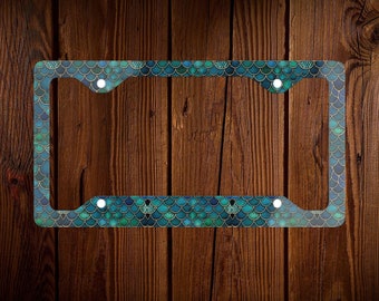 May include: A teal and gold license plate frame with a mermaid scale pattern.