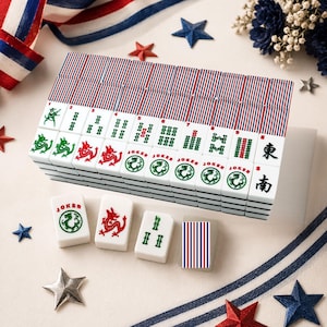 May include: A set of white mahjong tiles featuring red, white, and blue striped backs. The tiles display various green and red symbols, dragon illustrations, and the word Joker. Some tiles show Chinese characters for East and South directions.