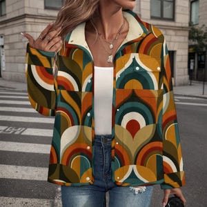 May include: A colorful jacket with a retro geometric pattern in shades of orange, brown, teal, and cream. The jacket has a cream-colored sherpa lining on the collar and cuffs, and is buttoned up. The jacket is paired with blue jeans.