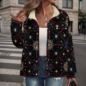 May include: Black button-up jacket with a cream-colored fleece lining and a celestial pattern. The jacket features a repeating design of stars, moons, and geometric shapes in red, blue, and gold. The jacket is worn over a white top and blue jeans.