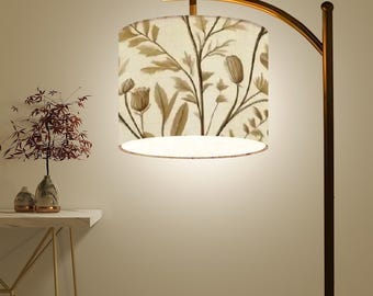May include: A gold floor lamp with a curved arm and a white drum lampshade with a brown floral pattern.