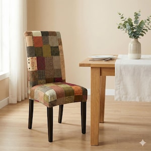 May include: A dining room chair with a patchwork design. The chair has a tall back and dark brown legs. The patchwork fabric features squares of various colors, including brown, green, red, and beige. The chair is positioned next to a wooden table.