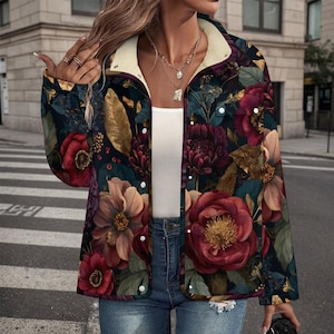 May include: A floral print jacket with a dark background and large red, pink, and purple flowers. The jacket has a cream-colored sherpa lining at the collar and white snap closures. The jacket is worn over a white top and blue jeans.