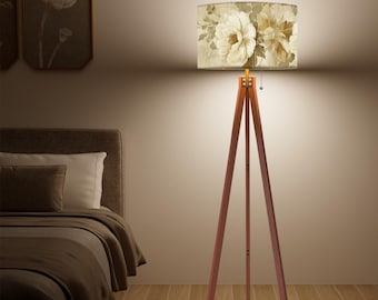 May include: A wooden tripod floor lamp with a beige lampshade featuring a floral pattern. The lampshade has a white and brown floral design.