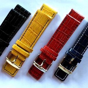 Puede incluir: Cuatro correas de reloj de cuero de diferentes colores con un patrón de cocodrilo. Las correas son negra, amarilla, roja y azul.