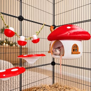 May include: A pet rat inside a white mushroom-shaped house with a red roof, mounted inside a black wire cage. The cage includes a red and white mushroom-themed garland, two red and white mushroom-shaped platforms, and a brown wooden window frame.