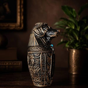 Side view of dog shaped canopic jar pet urn in black and gold cast stone