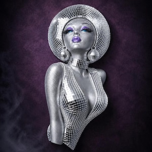 Könnte beinhalten: Silberne Büste einer Frau mit einem Design im Stil einer Discokugel. Die Büste hat einen großen, runden Hut, Ohrringe und einen tiefen Ausschnitt, die alle mit reflektierenden Quadraten bedeckt sind. Die Frau hat blaue Augen, lange Wimpern und lila Lippen, vor einem dunkelvioletten Hintergrund.
