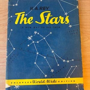 Puede incluir: Una cubierta de libro azul con un título amarillo "The Stars" y el texto "A New Way To See Them". La cubierta presenta un mapa de estrellas con constelaciones y el texto "Enlarged World-Wide Edition".