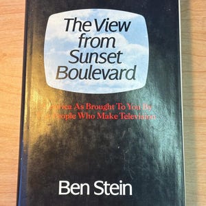 May include: A black book with the title "The View from Sunset Boulevard" in white text on a white television screen graphic. The subtitle is "America As Brought To You By The People Who Make Television" in red text. The author's name, "Ben Stein", is in white text at the bottom of the cover.