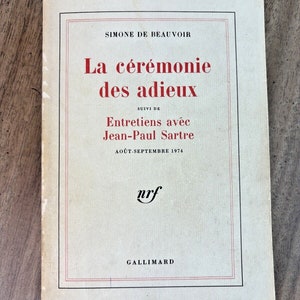 Könnte beinhalten: Ein weißer Buchumschlag mit rotem Text. Der Titel lautet "La cérémonie des adieux" von Simone de Beauvoir. Der Untertitel lautet "Entretiens avec Jean-Paul Sartre". Das Buch wurde im August-September 1974 veröffentlicht.