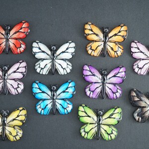May include: Assortment of 10 colorful butterfly embellishments with black outlines. The butterflies are made of plastic and have a glossy finish. They are perfect for adding a touch of whimsy to crafts, scrapbooking, and other projects.