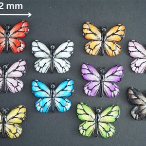 May include: Ten colorful butterfly embellishments, each measuring approximately 1 inch in diameter. The butterflies are made of plastic and have a glossy finish. The colors include red, white, yellow, blue, purple, and black.