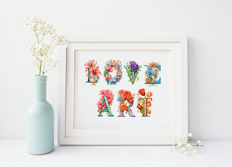 以下が含まれることがあります： 花で飾られたカラフルな文字で「LOVE ART」と書かれた白い額縁のプリント。文字はビンテージスタイルのフォントです。