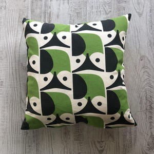 May include: Square cushion with a geometric pattern in black, white, and green. The design features abstract shapes, creating a modern look. The cushion is likely made of a soft fabric and is suitable for home decor. Approximately 40cm x 40cm.