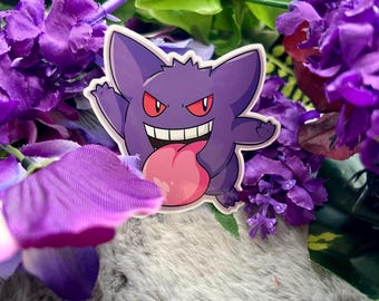 May include: Purple and pink cartoon ghost character with a wide grin and a large tongue sticking out. The character is on a white background.