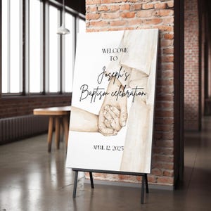 May include: A white sign with a watercolor illustration of two hands holding each other. The text on the sign reads "Welcome to Joseph's Baptism Celebration April 12, 2025".