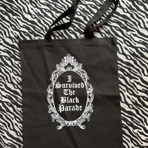 May include: Black tote bag with white text that reads "I Survived The Black Parade" inside a decorative white frame.