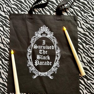 May include: Black tote bag with white text that reads "I Survived The Black Parade" inside a decorative frame.