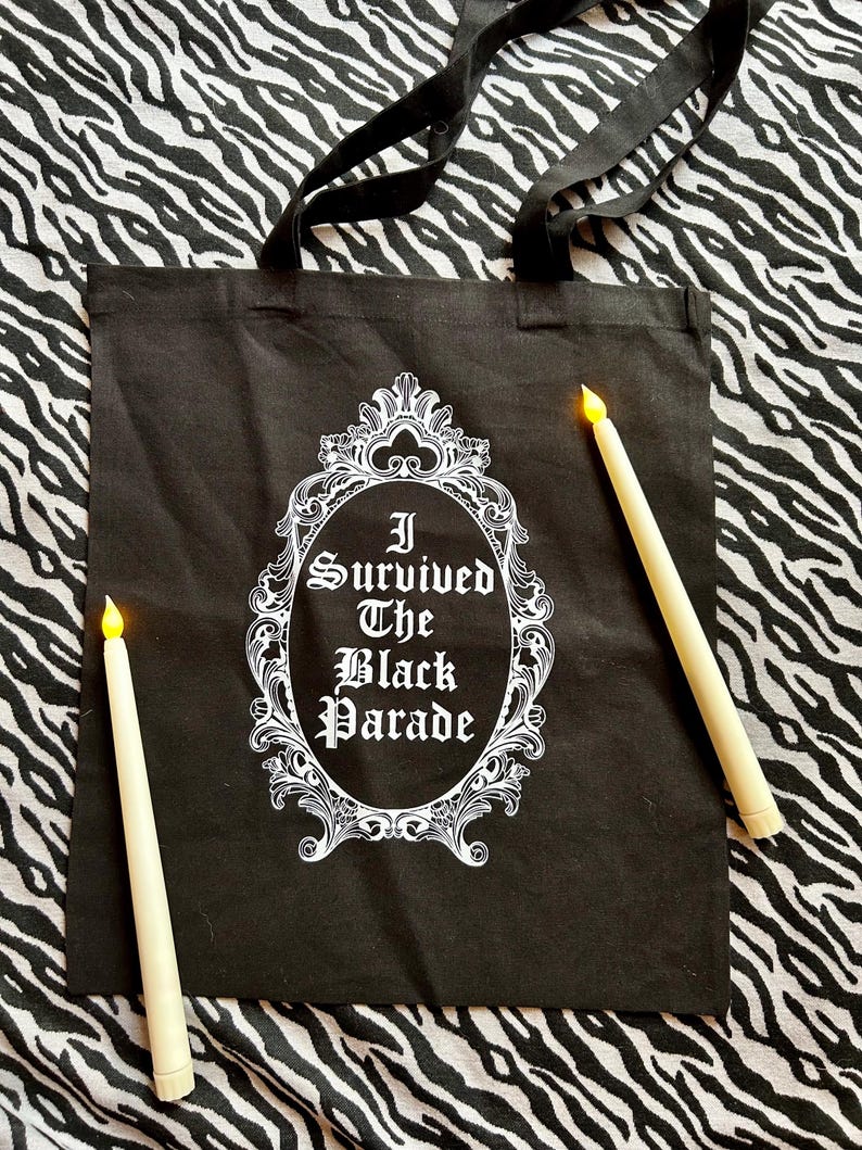 May include: Black tote bag with white text that reads "I Survived The Black Parade" inside a decorative frame.