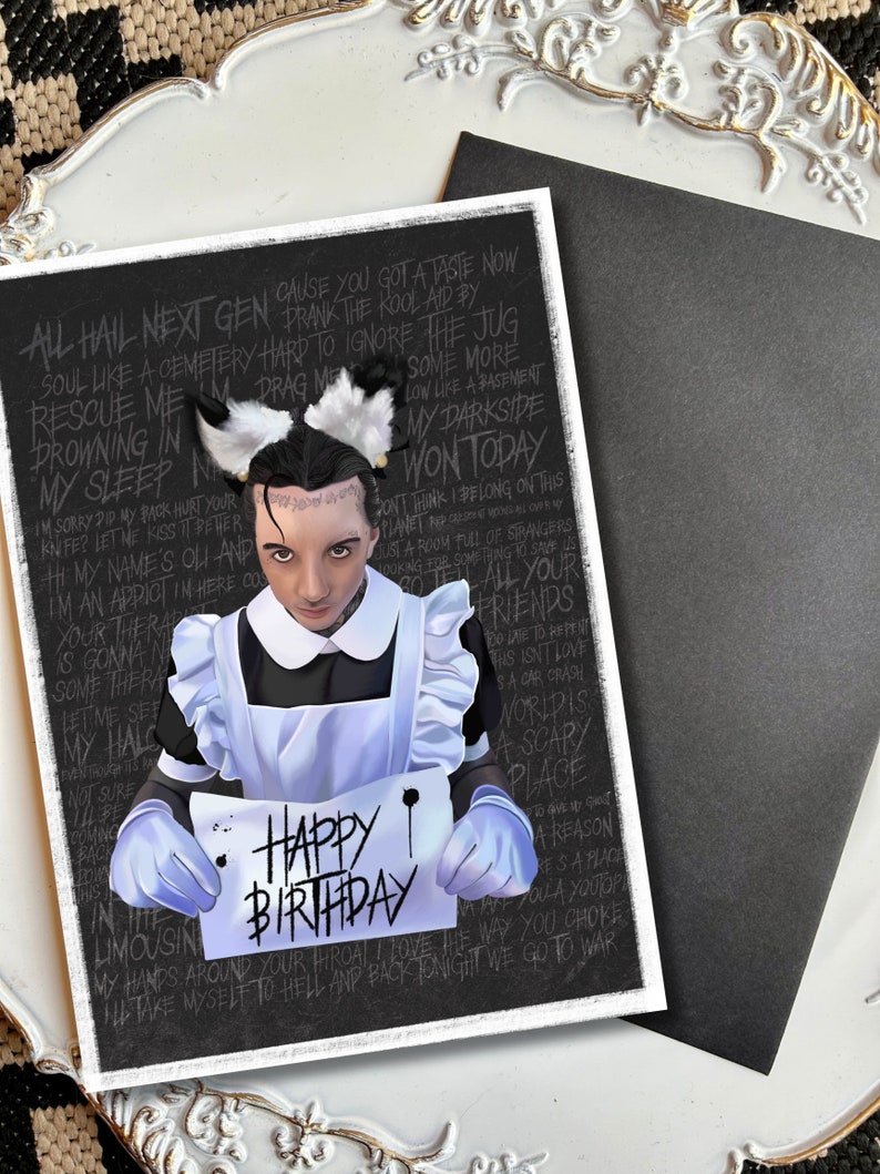 May include: A black and white birthday card featuring a person in a maid's outfit holding a sign that reads "Happy Birthday". The card has a black background with white text, including song lyrics.