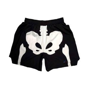 May include: Black shorts with a white skeleton pelvic bone design. The shorts have an elastic waistband and a small logo on the lower right leg. The shorts are made of a lightweight material.
