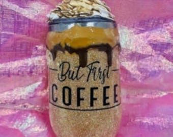 Könnte beinhalten: Ein goldener Glitzerbecher mit einem schwarz-weißen Design, auf dem "But First Coffee" steht. Der Becher hat einen braunen und weißen Deckel mit einem Schuss Schlagsahne oben drauf.