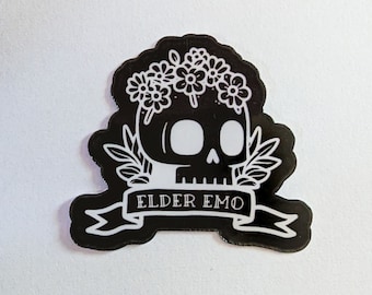 Puede incluir: Pegatina en blanco y negro con una calavera que lleva una corona de flores. El texto "ELDER EMO" se muestra en una pancarta debajo de la calavera. La pegatina tiene un borde irregular único.