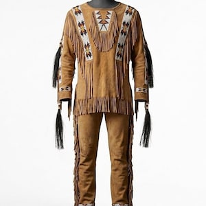 May include: A tan suede outfit consisting of a long-sleeved pullover and matching trousers. The pullover features a round neckline, long fringe trim, and white beaded panels with geometric patterns. Black hair tassels hang from the sleeves.
