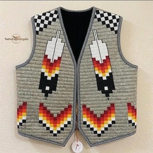 May include: A grey quilted vest featuring a black and white checkered pattern at the shoulders and a geometric feather design in white, red, orange, yellow, and black. The vest has a black interior lining and a small tag labeled NativeEagleRegalia.
