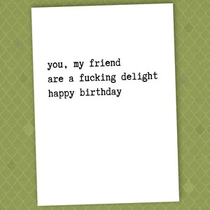 May include: A white greeting card with black text that reads: "you, my friend are a fucking delight happy birthday". The card is on a green background with a scale-like pattern.