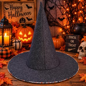 Puede incluir: Un sombrero de bruja alto y puntiagudo hecho de tela gris oscuro con un patrón continuo de líneas blancas finas que forman círculos superpuestos. El sombrero tiene un ala circular ancha y una corona cónica estructurada.