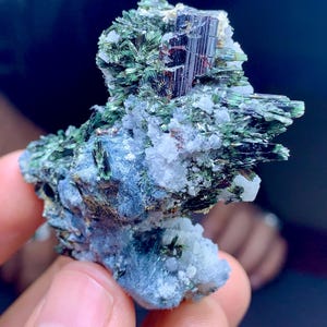 以下が含まれることがあります： 緑と黒の結晶の塊で、白い鉱物マトリックスがあります。結晶は鋭く、金属光沢があります。