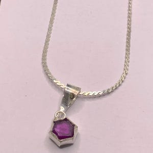 Könnte beinhalten: Eine silberne Kettenkette mit einem Anhänger mit einem violetten Edelstein.