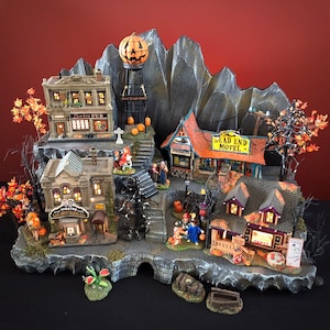 May include: A Halloween village scene with a pumpkin-shaped tower, a 'Zombie Pub', a 'Dead End Motel', and a 'Theatres Whispers Talking' building. The village is set on a rocky mountain base with a bridge and a small pumpkin patch.