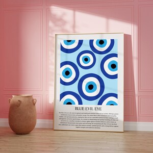 May include: A framed print with a blue background and a pattern of blue evil eyes. The text "BLUE EVIL EYE" is at the bottom of the print. The text below the title describes the meaning and history of the evil eye.