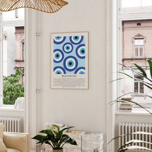 May include: A framed print with a blue and white pattern of evil eyes. The text "BLUE EVIL EYE" is at the bottom of the print. The print is hanging on a white wall.