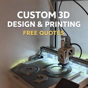 May include: A 3D printer in action, with the text "CUSTOM 3D DESIGN & PRINTING FREE QUOTES" in white and yellow. The machine is silver and white, with a detailed printing bed.