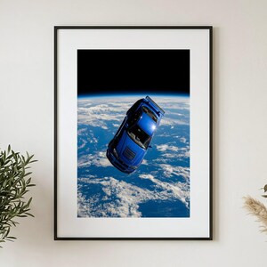 Könnte beinhalten: Ein gerahmter Kunstdruck, der einen leuchtend blauen Sportwagen zeigt, der im Weltraum über der Erde schwebt. Der Planet zeigt sichtbare weiße Wolken und blaue Ozeane vor dem dunklen schwarzen Weltraum, alles in einem dünnen schwarzen Rahmen.