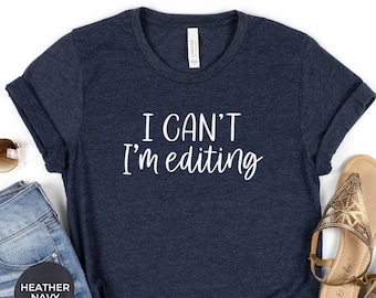 May include: A heather navy blue t-shirt with the text "I CAN'T I'M EDITING" in white.
