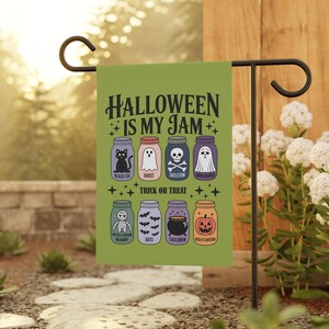 May include: A green Halloween garden flag with the text "HALLOWEEN IS MY JAM" and illustrations of Halloween characters in jars. The flag includes a black cat, ghost, skeleton, and Jack O'Lantern.