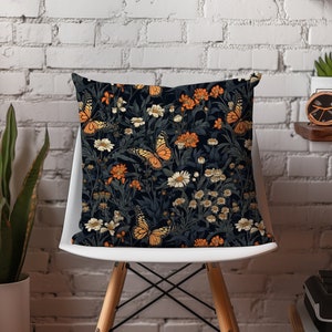 May include: A black and white throw pillow with a floral and butterfly pattern. The pillow features orange butterflies and white flowers on a dark background.