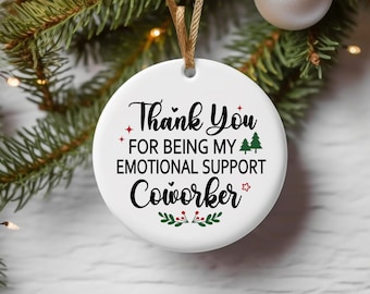 May include: White ceramic Christmas bauble with the text "Thank You for being my emotional support coworker" in black lettering with red stars and green pine trees.