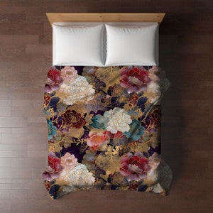 May include: A bed with a floral patterned comforter and two white pillows. The comforter features large flowers in shades of red, pink, white, and teal, with gold accents, set against a dark purple background. The bed frame is made of light wood.
