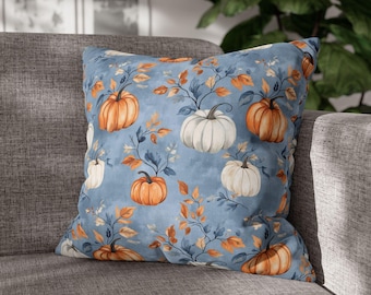 May include: A blue cushion with a pattern of white and orange pumpkins and autumn leaves.