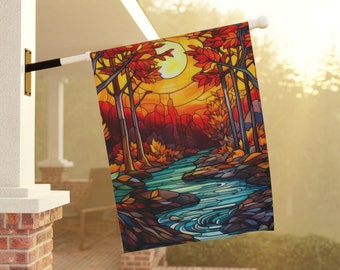 May include: A decorative outdoor flag with a stained-glass style autumn scene. The design includes a river, trees with red and orange leaves, and a large yellow sun. The flag is mounted on a white pole and displayed on a porch.