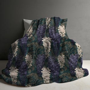 May include: A textile blanket featuring a repeating botanical pattern of deep purple and off-white wisteria-like flower clusters set against a dark teal background, interspersed with delicate, thin, golden-brown branching foliage.