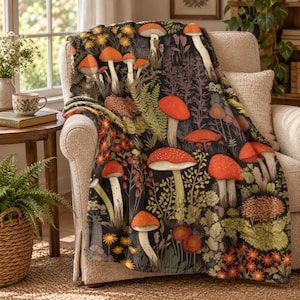 May include: A soft throw blanket featuring a dark background with a dense, colorful pattern of various red-capped mushrooms, green ferns, and small orange and yellow wildflowers scattered throughout the entire fabric surface.