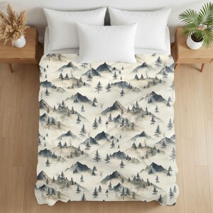 May include: A bedspread featuring a repeating watercolor pattern of dark gray mountain peaks and evergreen trees set against a cream-colored background. The design includes three white pillows placed at the head of the bedspread.